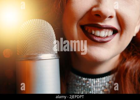 Smiling female singer's and retro microphone on bokeh blur background. Stock Photo