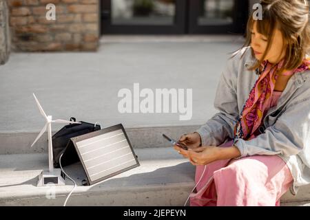 Woman charge phone from a portable solar panel Stock Photo