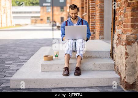 Stylish guy works on laptop computer on a street Stock Photo