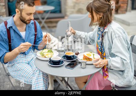 Stylish man and woman have delicious breakfast at cafe outdoors Stock Photo
