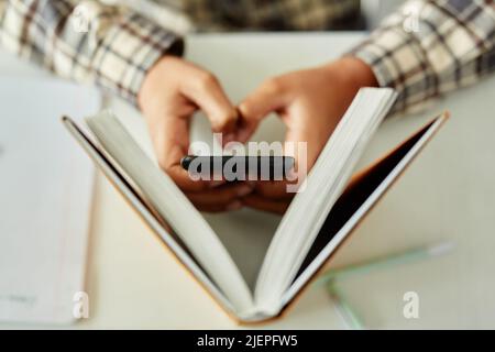 Top view closeup of unrecognizable kid hiding phone in school and cheating during class Stock Photo