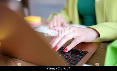 Female hands works on laptop keyboard in office Stock Photo