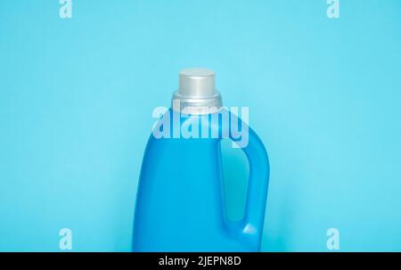 Blue plastic bottle stands on blue background. Conditioner or liquid powder for washing. Capacity with space for copying. Layout for logo application. Stock Photo