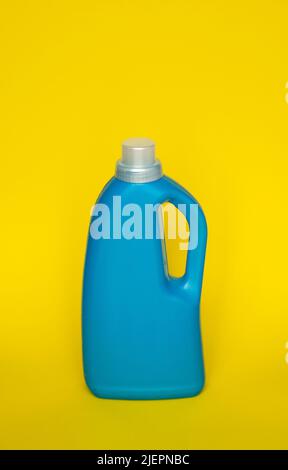 Blue plastic bottle stands on yellow background. Conditioner or liquid powder for washing. Capacity with space for copying. Layout for logo Stock Photo