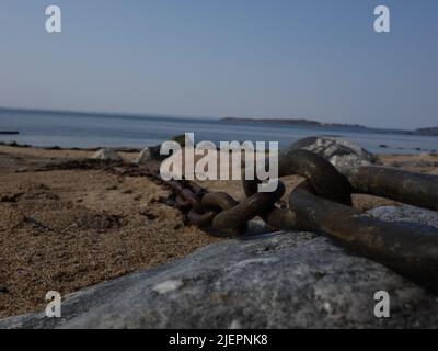 Metal chain lying in the sand on the beach. Stock Photo
