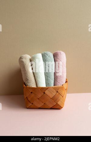 Towels in basket on pink table. beige wall background Stock Photo