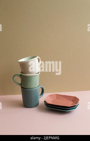 Stack of cups and dish on pink table. beige wall background Stock Photo