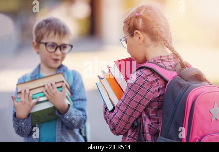 Girl and boy in glasses standing with books in their hands. Stock Photo