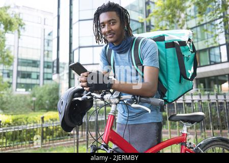 Portrait Of Corurier On Bike Delivering Takeaway Food Using Mobile Phone Stock Photo