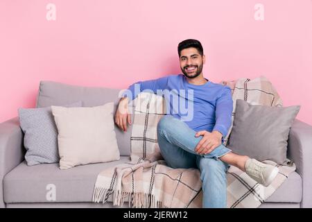 Photo of satisfied peaceful person sitting couch chilling toothy smile isolated on pink color background Stock Photo