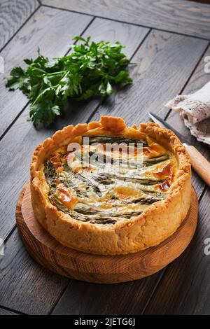 Quiche. Homemade asparagus pie or quiche with cheese and spinach on old dark wooden table background. Top view. Stock Photo