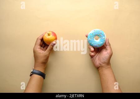 hand holding donuts and apple on hand on blue background  Stock Photo