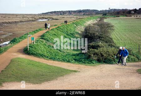 walkers on north norfolk coast path morston looking towards blakeney england Stock Photo