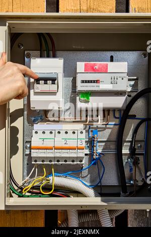 Turning circuit breaker in consumer unit with electrical meter. Stock Photo