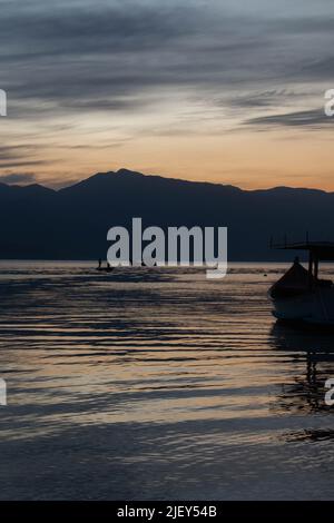 Incredible sunset over the sea, with small boats and the hills in the background, in Caieira da Barra do Sul, Stock Photo