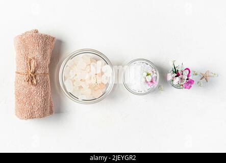 Towel, sea salt and flowers on a gray background. Stock Photo