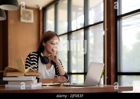 Successful freelancer taking note using laptop computer in at home. Portrait of skilled copywriter at workplace.Smiling student learning languages at Stock Photo