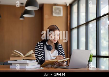 Successful freelancer taking note using laptop computer in at home. Portrait of skilled copywriter at workplace.Smiling student learning languages at Stock Photo