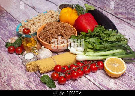 Italian pasta with vegetables, olive oil, spices on a wooden background. Stock Photo