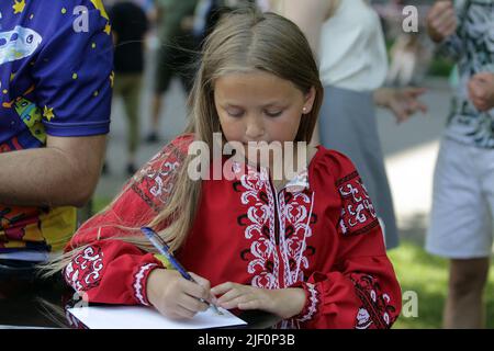 Kiev, Ukraine - June 28, 2022 - Sofiia Kravchuk, 11, whose drawing was used for the Ukrainian Dream postage stamp, envelope and postcard, signs envelopes during the start of sales outside the Central Post Office in Maidan Nezalezhnosti on Constitution Day, Kyiv, capital of Ukraine. Sofiia Kravchuk from Liuboml, Volyn Region, depicted the Antonov An-225 Mriya aircraft in a drawing submitted to the What Does Ukraine Mean to Me? contest held in 2021, the year marking 30 years of Ukraine's independence. The An-225 Mriya ( (a 'dream' in Ukrainian) was destroyed in the Battle of Antonov Airport duri Stock Photo