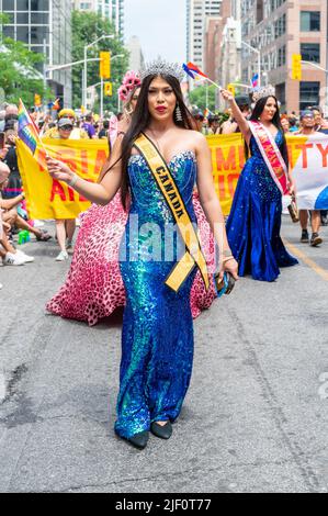 A beautiful woman with a sign reading Canada walks leading a group of people during the Pride Parade Stock Photo