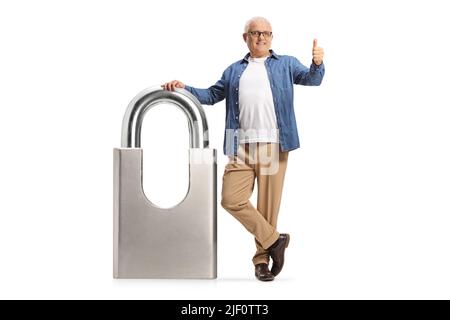 Mature man leaning on a silver padlock and showing thumbs up isolated on white background Stock Photo