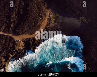Aerial view of beach with lava and ocean waves with sunset tones at Lanzarote island Stock Photo