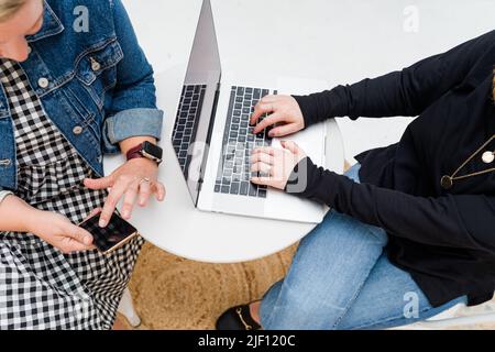 View from above of two women's hands working on computer and phone Stock Photo