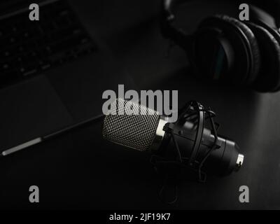 On a black background, a studio microphone and studio headphones. Close-up. Radio, journalism, presentation, sound work, recording studio, podcast. Ad Stock Photo