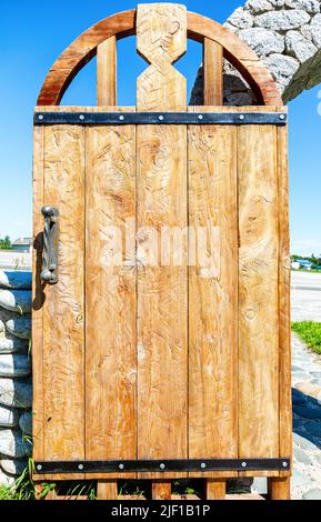 Massive handmade rough wooden door with metal handle close up Stock Photo