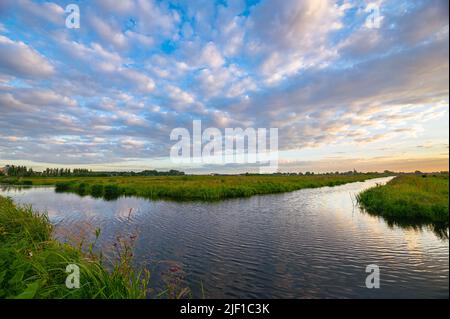 Altocumulus sheep clouds over water-filled ditches and grasslands in the Dutch countryside Stock Photo