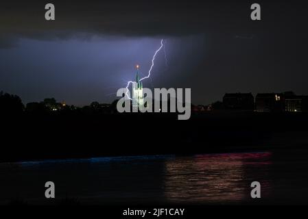 Lightning bolt strikes behind a church near a river Stock Photo