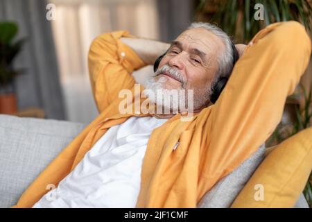 Good-looking elderly man enjoying newest wireless headset at home Stock Photo