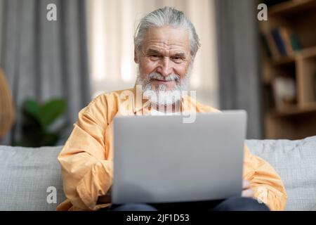 Happy old man using notebook at home Stock Photo