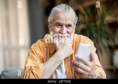 Cheerful senior man using smartphone at home Stock Photo