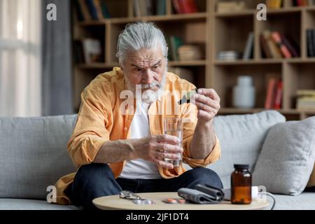 Sick elderly man suffering from hypertension, using medicine Stock Photo
