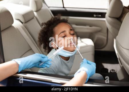 Black Preteen Girl Getting Tested For Covid-19 Sitting In Car Stock Photo