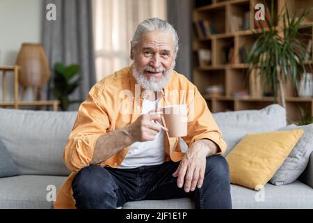 Senior man drinking coffee and smiling, home interior Stock Photo