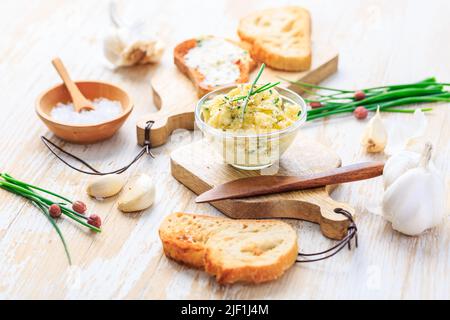 Homemade garlic butter with herbs and chives and fresh roasted baguette with salt Stock Photo