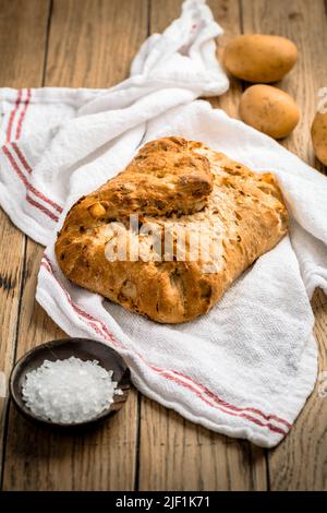 Potato bread with spelt flour and roasted onions on wooden table Stock Photo