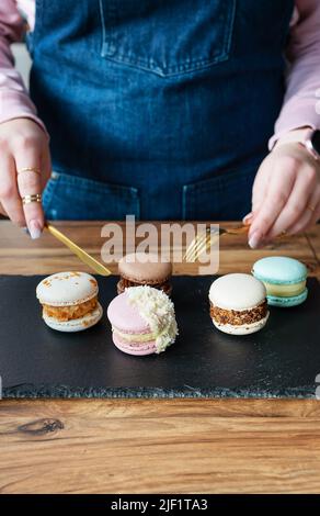 A delicious pasta dessert - a French sweet delicacy lies on a concrete black stand and a girl with a knife and fork cuts sweets Stock Photo