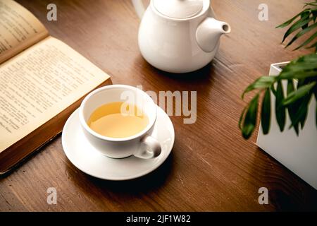 Close-up, a cup of tea and a book on a wooden table. Stock Photo