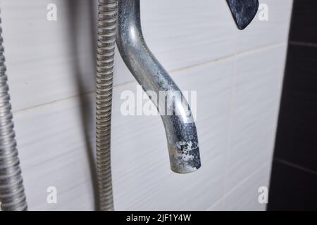 A thin stream of hard water flows from an old tap aerator. Old Bathroom Sink Faucet contaminated with calcium and grime Stock Photo