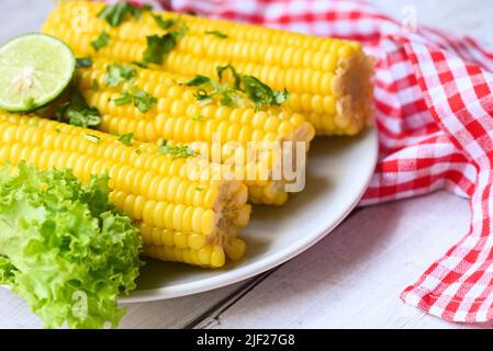sweet corn food with salad vegetable lime coriander and lettuce, sweet corn cooked on white plate background, ripe corn cobs steamed or boiled sweetco Stock Photo