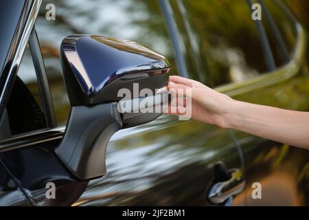 Driver hands adjusting side view mirror of a car. Stock Photo