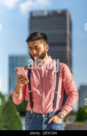 Serious and relaxed businessman using mobile outside a business center. Stock Photo