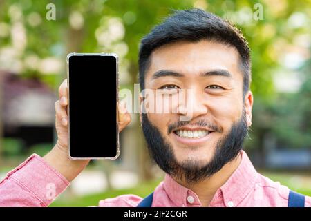 Asian man showing the screen of mobile phone while smiling Stock Photo