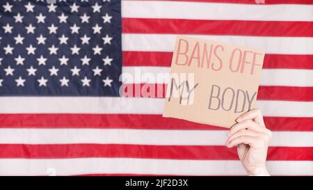 Woman holding a sign My Body, My Choice American flag on background. Protest against anti abortion law. Women's strike. Womens rights freedom. Stock Photo