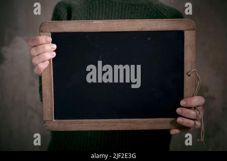 Crop unrecognizable female showing mock up of blackboard in wooden frame in hands Stock Photo