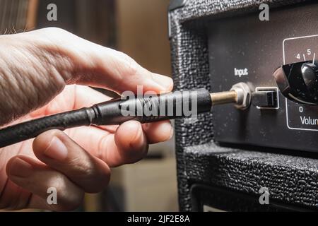 Plugging an instrument cable into a guitar amplifier Stock Photo